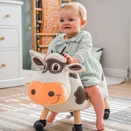Toddler boy playing his friend Little Bird Told Me Moobert Cow Ride On Toy in a natural cream Scandi nursery | Baby Walkers and Ride On Toys | Montessori Activities For Babies & Kids | Toys | Baby Shower, Birthday & Christmas Gifts - Clair de Lune UK