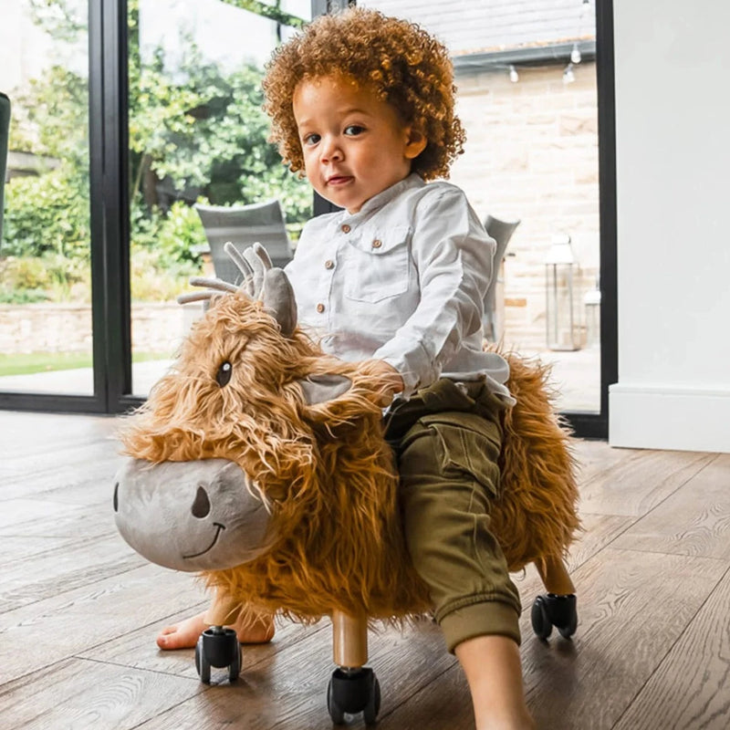Little boy racing on his Little Bird Told Me Hubert Highland Cow Ride On Toy | Baby Walkers and Ride On Toys | Montessori Activities For Babies & Kids | Toys | Baby Shower, Birthday & Christmas Gifts - Clair de Lune UK
