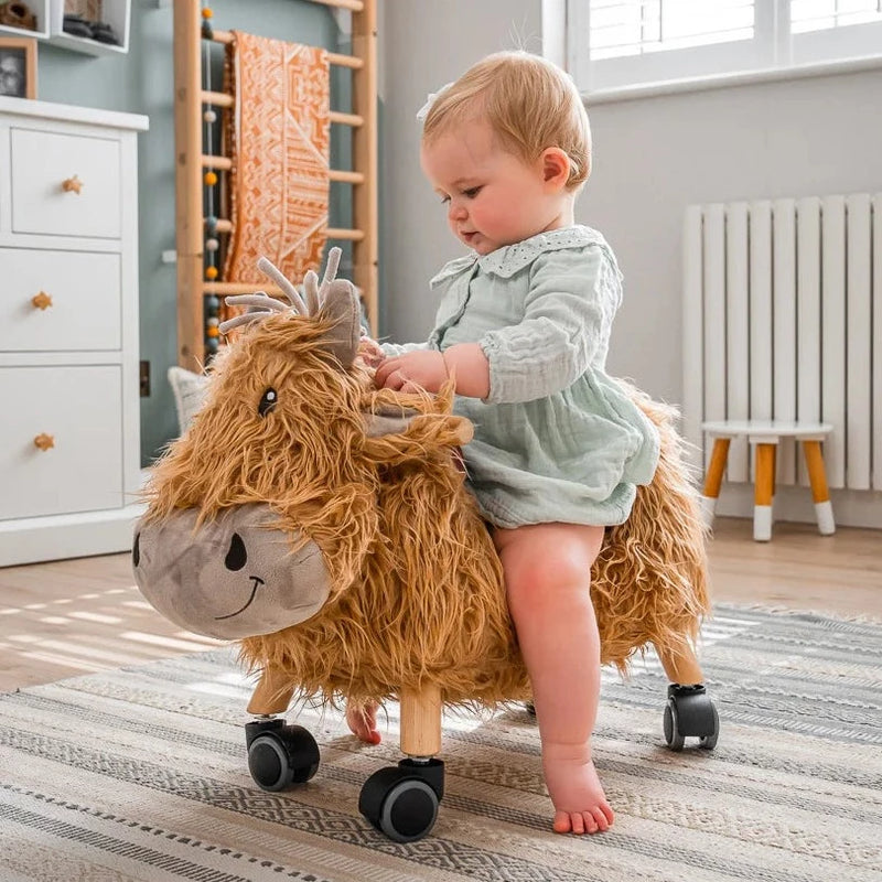 Toddler boy playing with the fur of the Little Bird Told Me Hubert Highland Cow Ride On Toy helping improve his sensory skills | Baby Walkers and Ride On Toys | Montessori Activities For Babies & Kids | Toys | Baby Shower, Birthday & Christmas Gifts - Cla