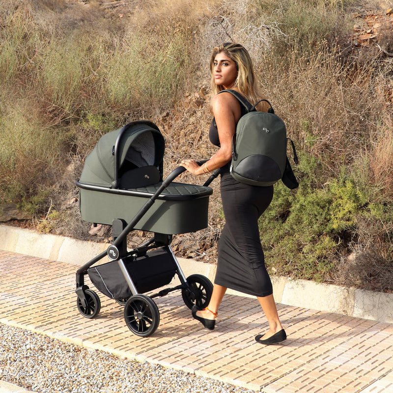 Mum wearing the matching changing bag while pushing the Forest Green My Babiie 3-in-1 Travel System with i-Size Car Seat | Pushchairs and Travel Systems | Baby & Kid Travel - Clair de Lune UK