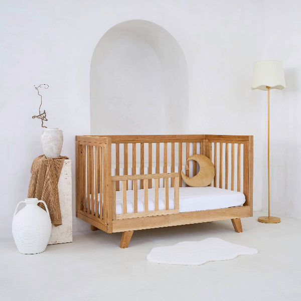 Solid Oak Cot Bed in the a Stylish White Minimalist Nursery by a Lamp | Cot Bed & Toddler Beds | Nursery Furniture - Clair de Lune UK