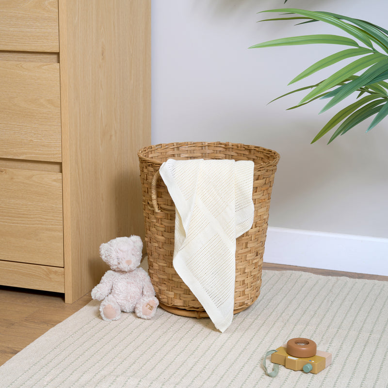 Cream Organic Cotton Cellular Blanket over a wicker basket next to an oak changing unit | Cosy Baby Blankets | Nursery Bedding | Newborn, Baby and Toddler Essentials - Clair de Lune UK