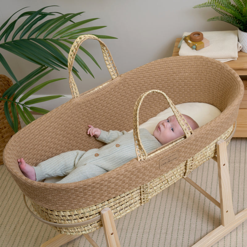 Newborn baby wearing a grey onsie sleeping in the Biscuit Brown Organic Knitted Palm Moses Basket and rocking stand | Moses Baby Baskets, Bassinets | Organic Baby Essentials | Nursery Furniture - Clair de Lune UK