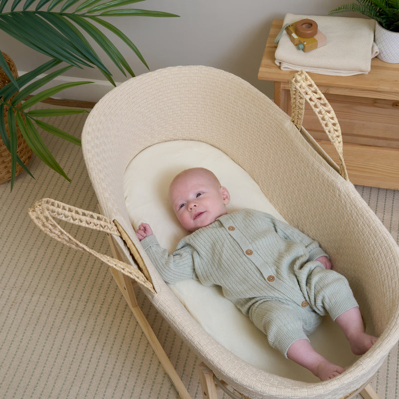 Baby wearing a grey onsie in the cream Organic Knitted Palm Moses Basket by green plants | Moses Baby Baskets, Bassinets | Organic Baby Essentials | Nursery Furniture - Clair de Lune UK