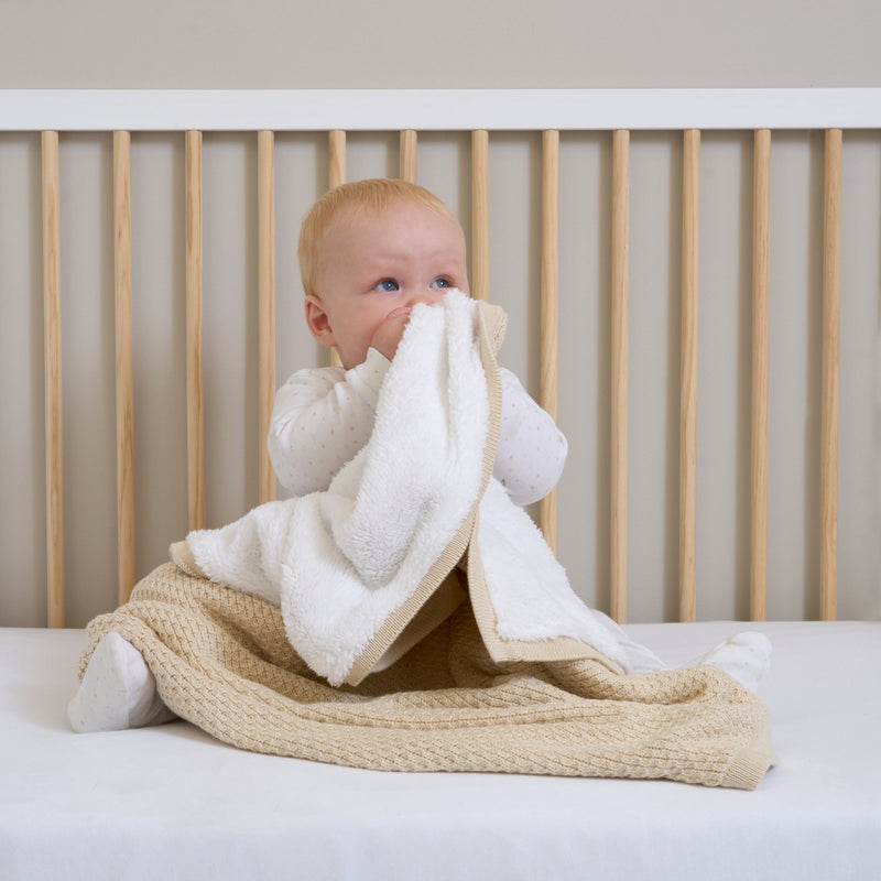 Baby boy sat up in the Essentials Cot Bed Snuggling with the Organic Knit Sherpa Blanket in Cream | Cosy Baby Blankets | Swaddles | Baby Winter Warmers - Clair de Lune UK