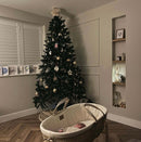 Decorated Christmas tree in a living room by a newborn baby in an organic palm moses basket | Baby's First Christmas - Clair de Lune UK