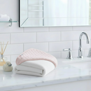 Pink Marshmallow Hooded Baby Towel folded by a sink in a white bathroom | Baby Hooded Towels | Baby Bath Time Essentials - Clair de Lune UK