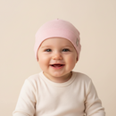 Baby wearing the GrowGrows Pink Pinstripe Baby Hat smiling at the camera | Bamboo Babywear - Clair de Lune UK