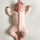 Newborn baby lying down in a Pink Pinstripe Sleepsuit with classic pink stripe design made from bamboo and organic cotton from GrowGrows - Clair de Lune UK