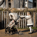 Feather Roma Egg® Dolls Pram Fur Hood and Double Hand Muff showcasing kid pushing the Egg doll pram and enjoying the snuggly kid double hand muff in the sunshine | Toys | Birthday & Christmas Gifts - Clair de Lune UK