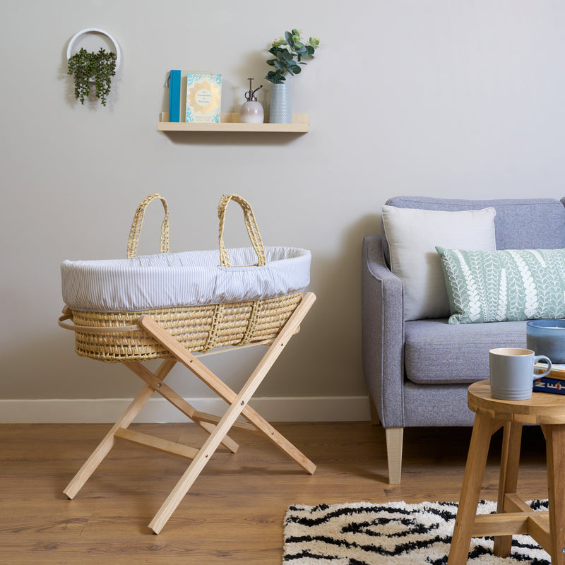 Grey Stripe Palm Moses Basket on Folding Stand in the Living Room next to grey sofa | Bassinets | Nursery Furniture - Clair de Lune UK