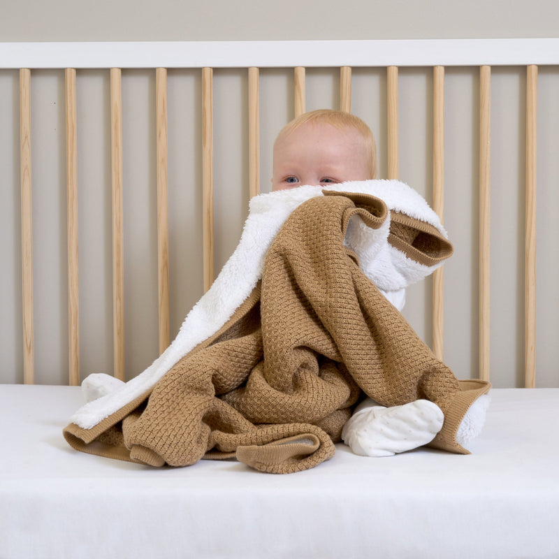 Baby boy sat up in the Essentials Cot Bed Snuggling with the Organic Knit Sherpa Blanket in Biscuit Brown | Cosy Baby Blankets | Swaddles | Baby Winter Warmers - Clair de Lune UK