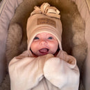 Newborn baby girl smiling wearing the oatmeal star fleece baby wrap blanket getting ready for an outdoor adventure | Cosy Baby Blankets | Swaddle Blanket | Nursery Bedding - Clair de Lune UK