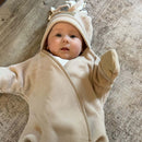 Baby wearing an oatmeal brown star fleece wrap blanket with the tassel hood up | Baby Blankets and Swaddles - Clair de Lune UK