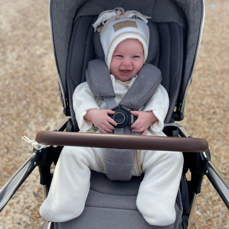 Smiling baby wearing the cream Star Fleece Baby Wrap Blanket while staying in his pushchair | Cosy Baby Blankets | Nursery Bedding | Newborn, Baby and Toddler Essentials - Clair de Lune UK