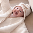 Beautiful baby wearing the cream Star Fleece Baby Wrap Blanket laughing all snuggled up | Cosy Baby Blankets | Swaddle Blanket | Nursery Bedding - Clair de Lune UK