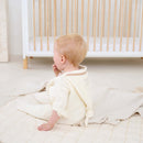 Baby Wearing the Cream Organic Star Breathable Mesh Baby Wrap Blanket while sat on the floor of the beige nursery | Cosy Baby Blankets and Swaddles | Newborn Summer Essentials - Clair de Lune UK
