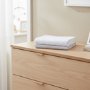 Stars & Stripes Fitted Pram/Crib Sheets folded on an oak set of drawers in a beige nursery | Soft Baby Bedding | Crib Bedding - Clair de Lune UK