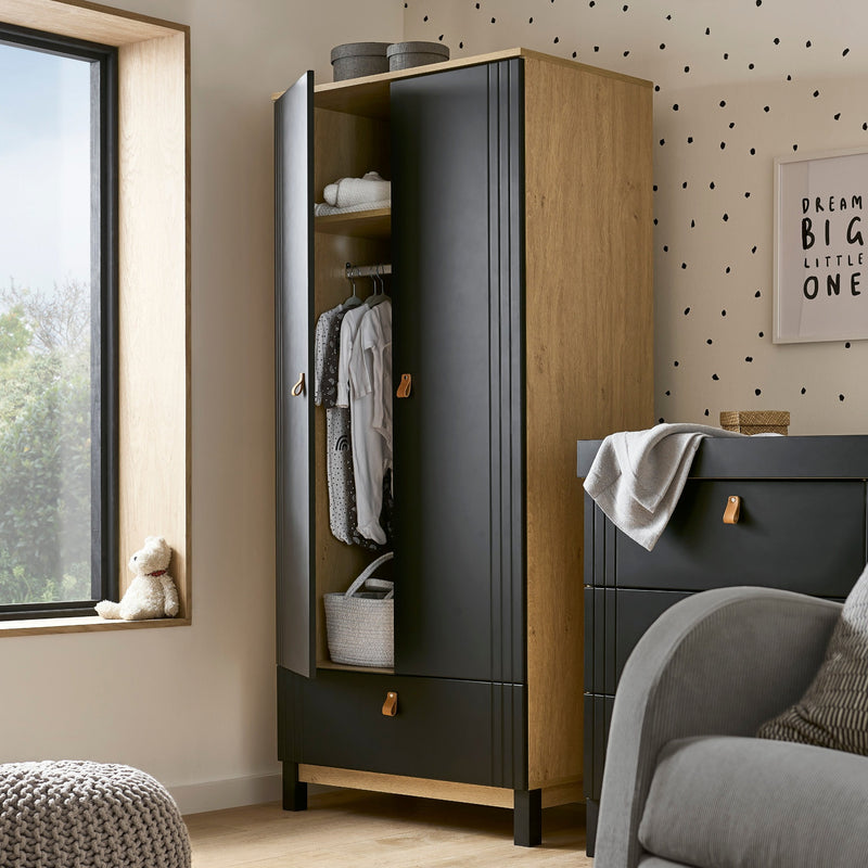 Black and Natural CuddleCo Rafi Freestanding Double Wardrobe with Drawer in a cream monochrome nursery with full of baby clothes | Wardrobes & Shelves | Storage Solutions | Nursery Furniture - Clair de Lune UK