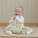 Baby smiling and holding the Cream Organic Knitted Blanket | Baby Blankets and Swaddles - Clair de Lune UK