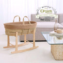 Biscuit Brown Organic Knitted Palm Moses Basket on natural rocking stand in a white ultra stylish minimalist living room next to an organic cork and glass coffee table | Platinum Award Winner 2025 | Moses Baby Baskets, Bassinets | Organic Baby Essentials | Nursery Furniture - Clair de Lune UK