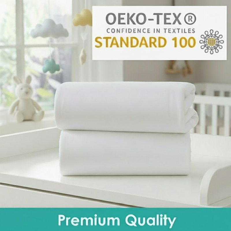 Stack of Cot Bed Sheets in White showing they're OEKO-TEX certified in the nursery next to the Essentials Cot Bed | Soft Baby Sheets | Cot & Cot Bed Bedding | Nursery Linen - Clair de Lune UK