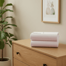 White 2 pack pram/crib fitted sheets folded on a chest of drawers in a beige nursery | Soft Baby Sheets | Crib Bedding - Clair de Lune UK