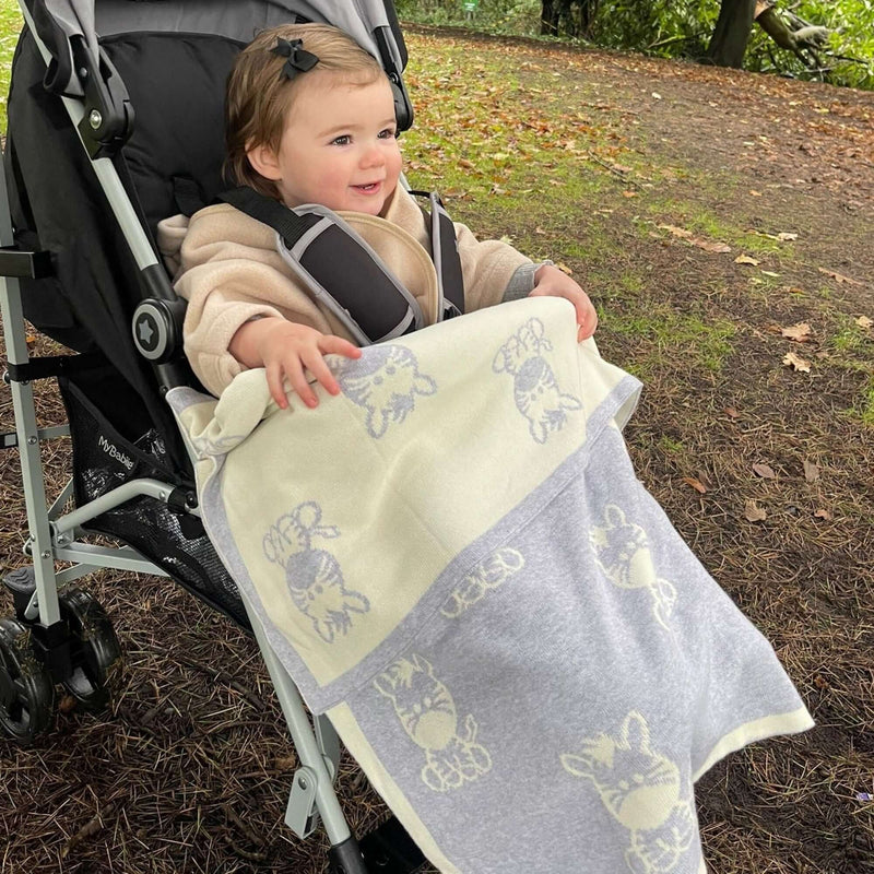  Baby smiling while wearing the Reversible Zebra Knitted Blanket on her pushchair | Cosy Baby Blankets | Nursery Bedding | Newborn, Baby and Toddler Essentials - Clair de Lune UK
