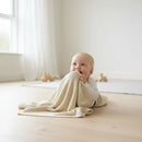 Baby smiling and holding the Cream Organic Knitted Blanket | Baby Blankets and Swaddles - Clair de Lune UK