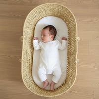 Baby lying on a Quilted Hypoallergenic Moses Basket Mattress in a Palm Moses Basket | Moses Basket Accessories | Nursery Furniture - Clair de Lune UK