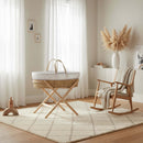Special Buy - Lullaby Hearts Palm Moses Basket with Stand Bundle on in a bright and airy beige nursery next to a nursing chair | Moses Baby Baskets & Bassinets | Nursery Furniture - Clair de Lune UK
