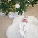 Baby wearing the cream Star Fleece Baby Wrap Blanket with hood up and mittens over their hands smiling under the gold and cream christmas tree | Cosy Baby Blankets | Swaddle Blanket | Baby's First Christmas Gift - Clair de Lune UK