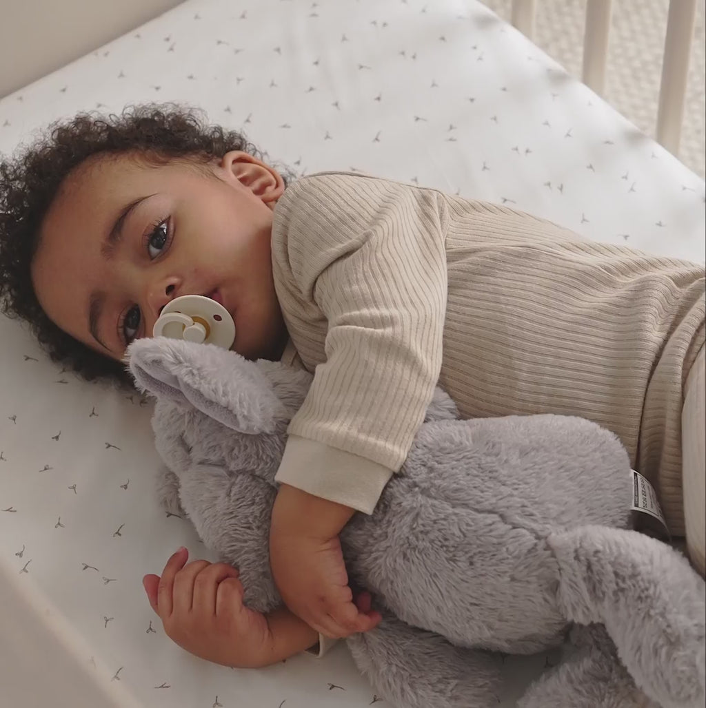 Baby relaxing and playing in the Cot Bed part of the Cashmere CuddleCo Clara 3 Piece Nursery Furniture Set in a cosy neutral nursery | Nursery Furniture | Cot Bed - Clair de Lune UK