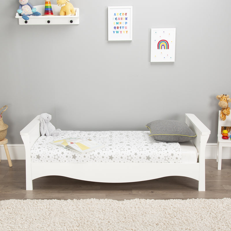 The cot bed transformed to a toddler bed of the White CuddleCo Clara 2pc Nursery Set - 3 Drawer Dresser/Changer & Cot Bed in a grey gender-neutral nursery | Nursery Furniture Sets | Room Sets | Nursery Furniture - Clair de Lune UK