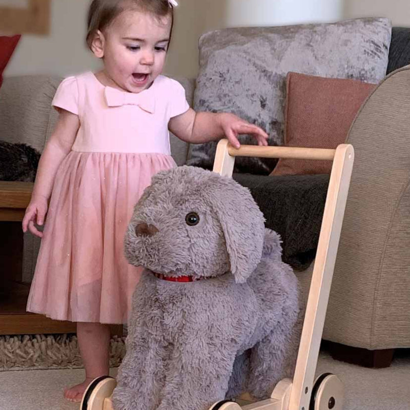 Baby girl is excited next to the Little Bird Told Me Bailey Dog Push Along, Baby Walker and Ride On | Montessori Activities For Babies & Kids | Toys | Baby Shower, Birthday & Christmas Gifts - Clair de Lune UK