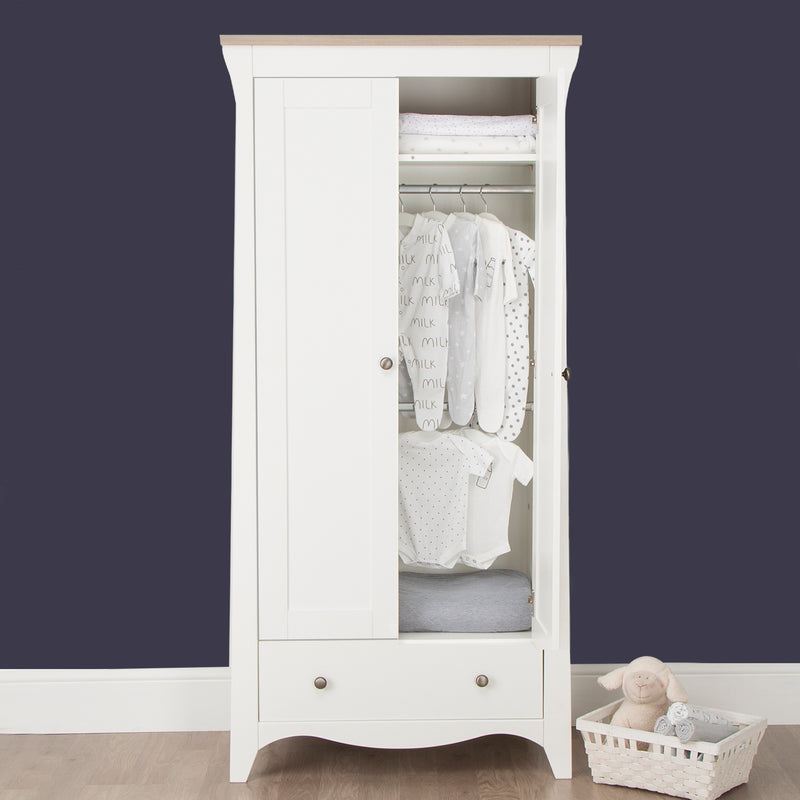 Open White and Natural CuddleCo Clara 2 Door Double Wardrobe with baby clothes in front of a dark blue navy wall | Wardrobes & Shelves | Storage Solutions | Nursery Furniture - Clair de Lune UK