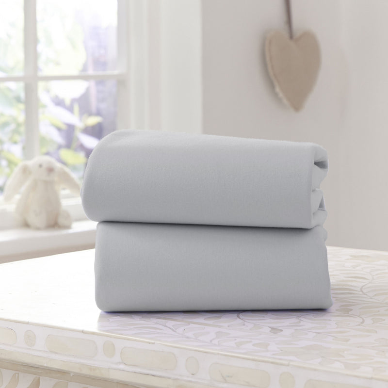 A Pack of 2 Folded Grey Fitted Cotton Moses Fitted Sheets - 74 x 30 cm on the countertop | Soft Baby Sheets | Cot, Cot Bed, Pram, Crib & Moses Basket Bedding - Clair de Lune UK