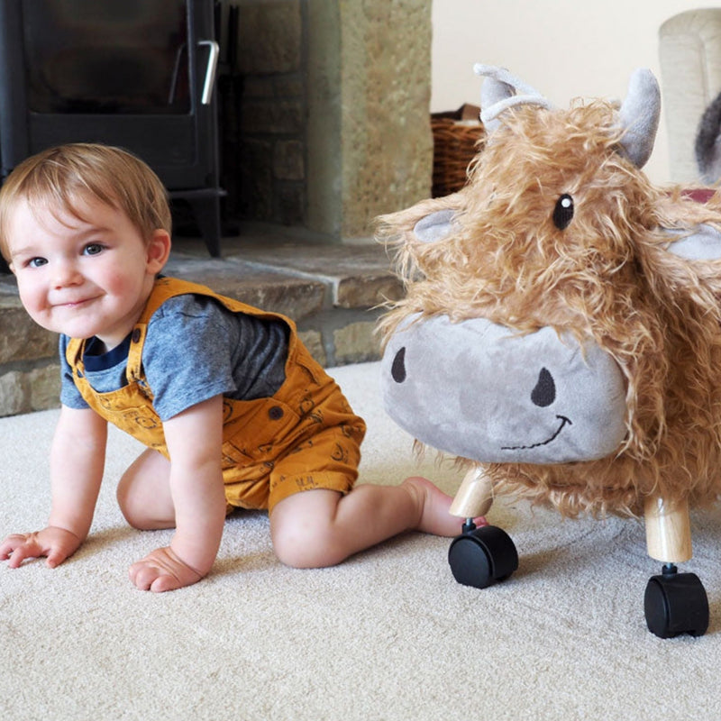 Toddler boy next to his favourite toy Little Bird Told Me Hubert Highland Cow Ride On Toy | Baby Walkers and Ride On Toys | Montessori Activities For Babies & Kids | Toys | Baby Shower, Birthday & Christmas Gifts - Clair de Lune UK