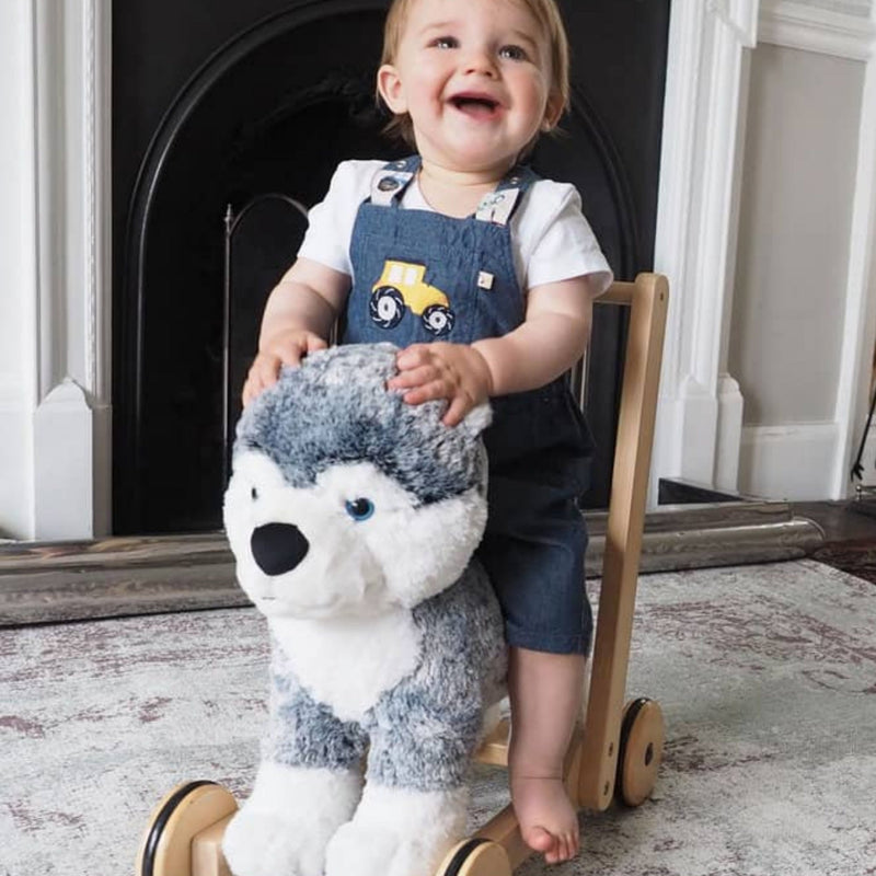 Toddler girl is laughing happily while riding the Little Bird Told Me Mishka Dog 2in1 Push Along, Baby Walker and Ride On | Baby Walkers and Ride On Toys | Montessori Activities For Babies & Kids | Toys | Baby Shower, Birthday & Christmas Gifts - Clair de