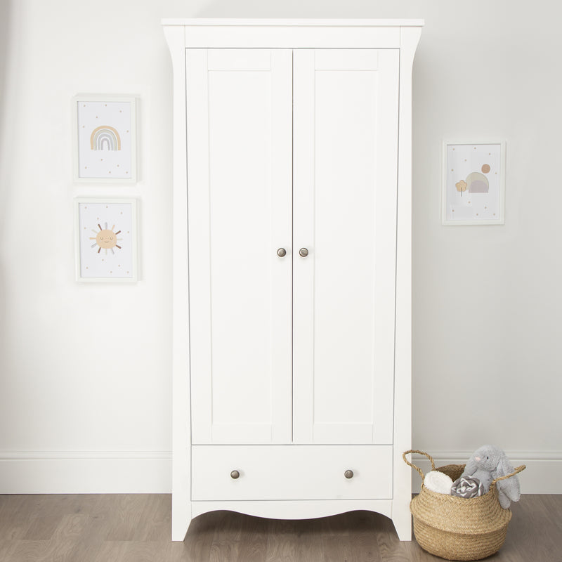 Closed White CuddleCo Clara 2 Door Double Wardrobe with baby clothes in front of a grey wall | Wardrobes & Shelves | Storage Solutions | Nursery Furniture - Clair de Lune UK